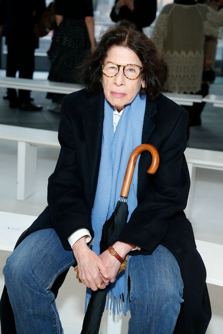 an older woman sitting on a bench holding an umbrella