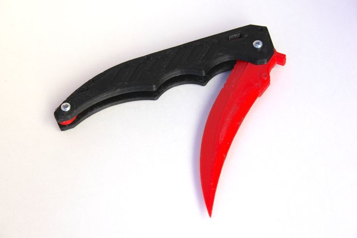 a black and red knife laying on top of a white table