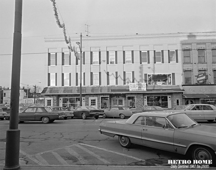 an old black and white photo of cars parked in front of a building on a street corner