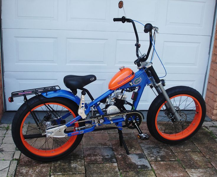 an orange and blue motorcycle parked in front of a garage door