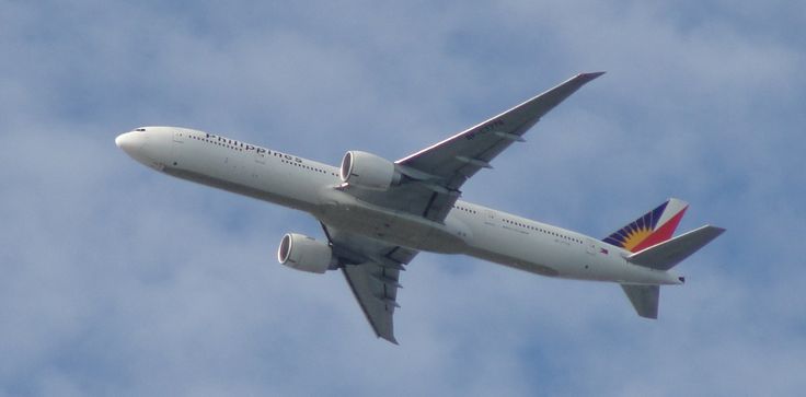 an airplane is flying in the air on a cloudy day with blue skies behind it