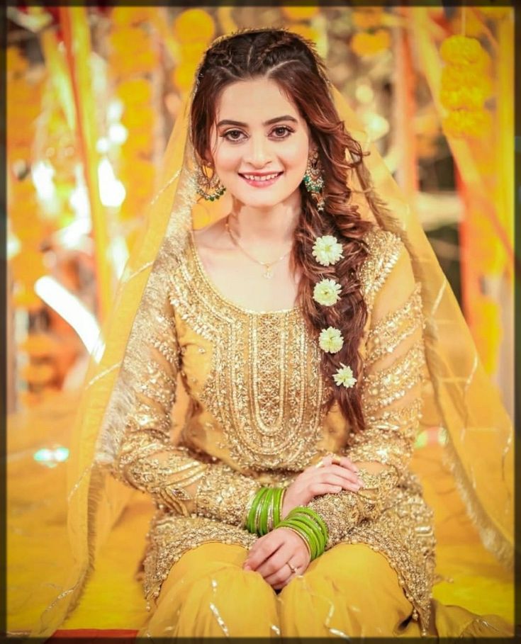 a woman sitting on the ground wearing a yellow outfit and green bracelets with flowers in her hair