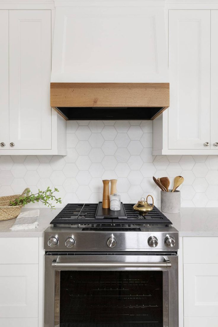 a stove top oven sitting inside of a kitchen next to white cabinets and counter tops