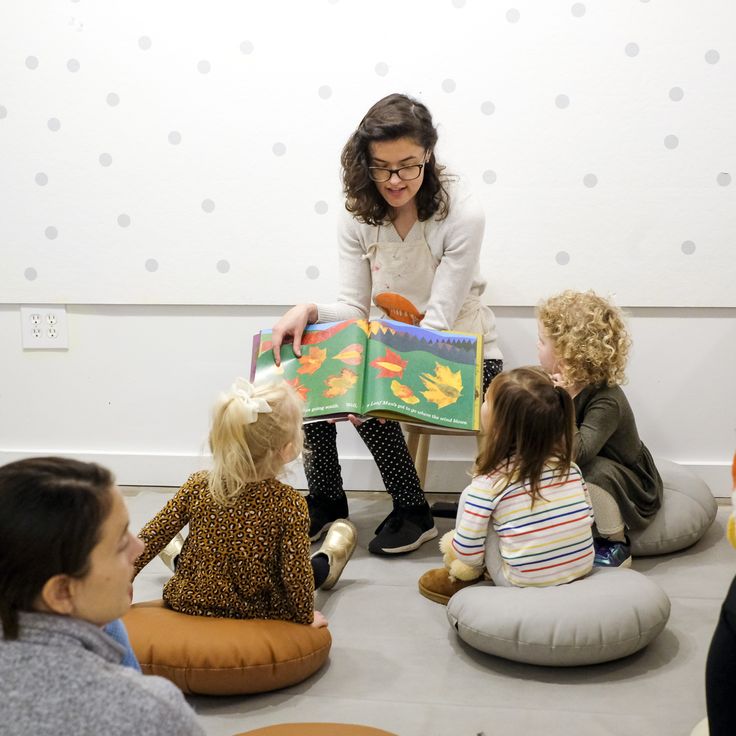 a woman reading to children sitting on bean bags