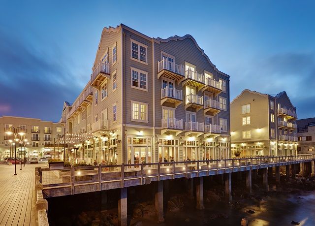 the boardwalk is lit up at night with buildings in the background