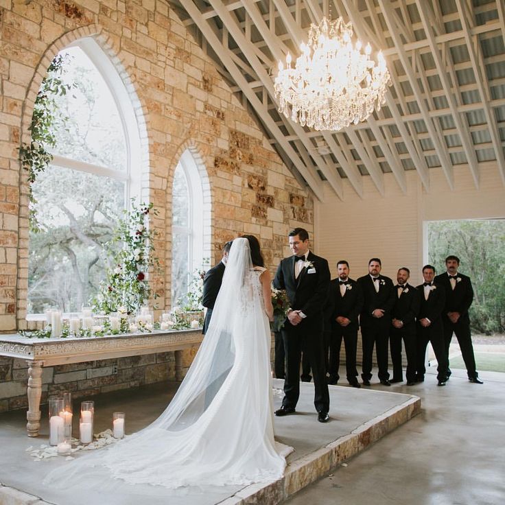 a bride and groom standing in front of their wedding party at the alter with candles lit