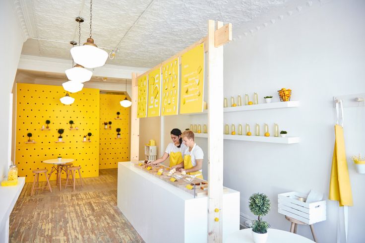 two people standing at the counter in a yellow and white shop