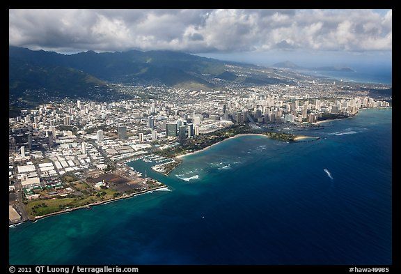 an aerial view of a city and the ocean with clouds in the sky over it