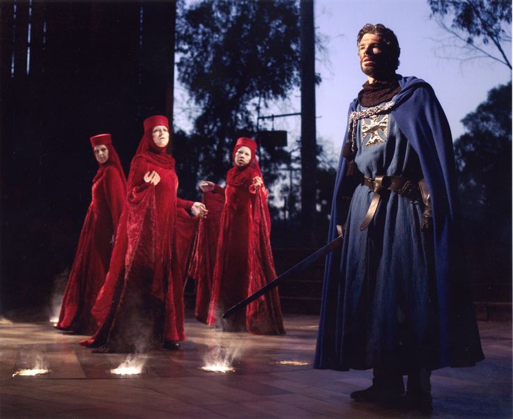 three people dressed in red robes and holding swords