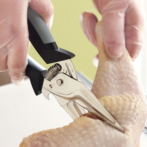 a person cutting chicken with a pair of scissors