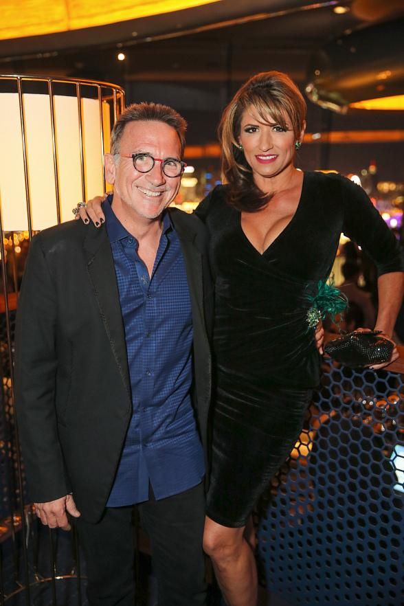 a man and woman standing next to each other in front of a metal fence at an event