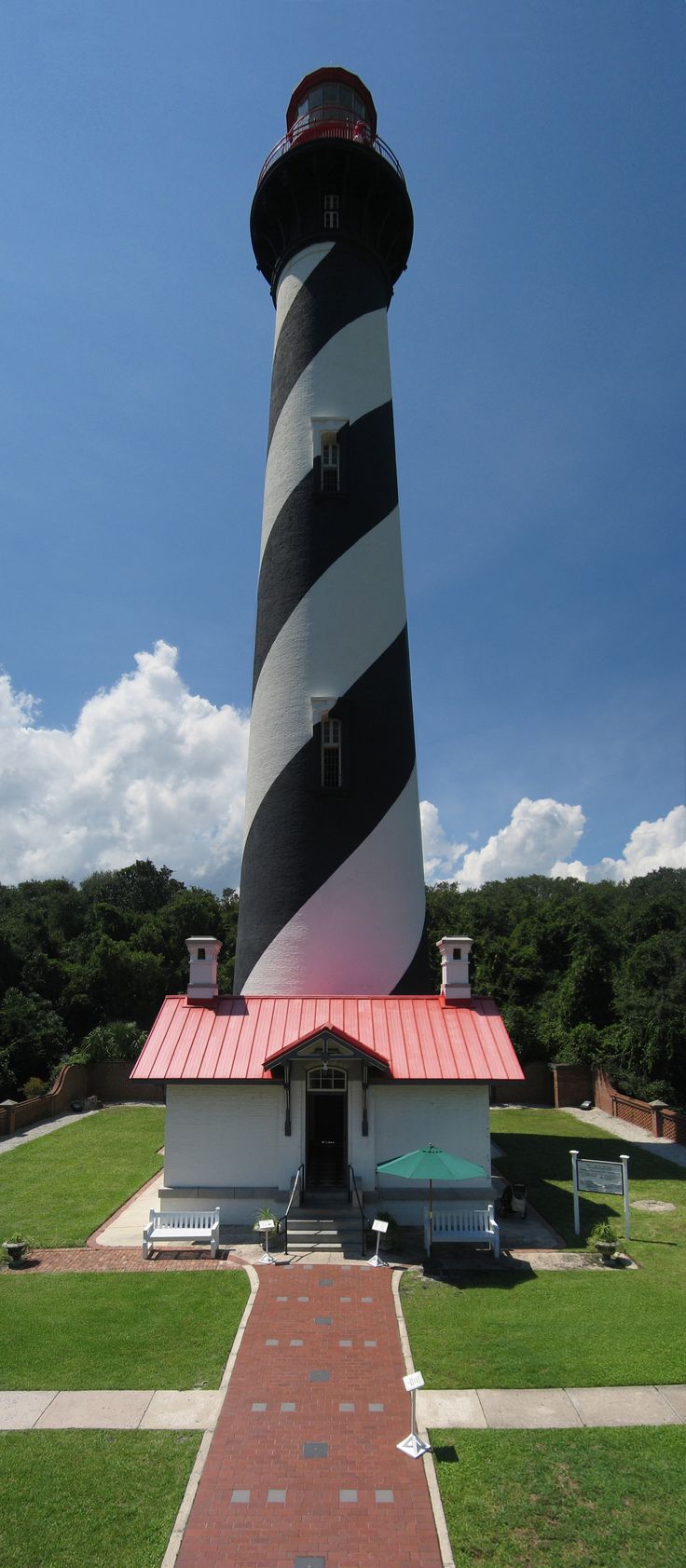 a large black and white lighthouse on top of a green field