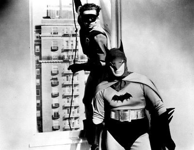 two men dressed as batman standing next to each other in front of a computer tower