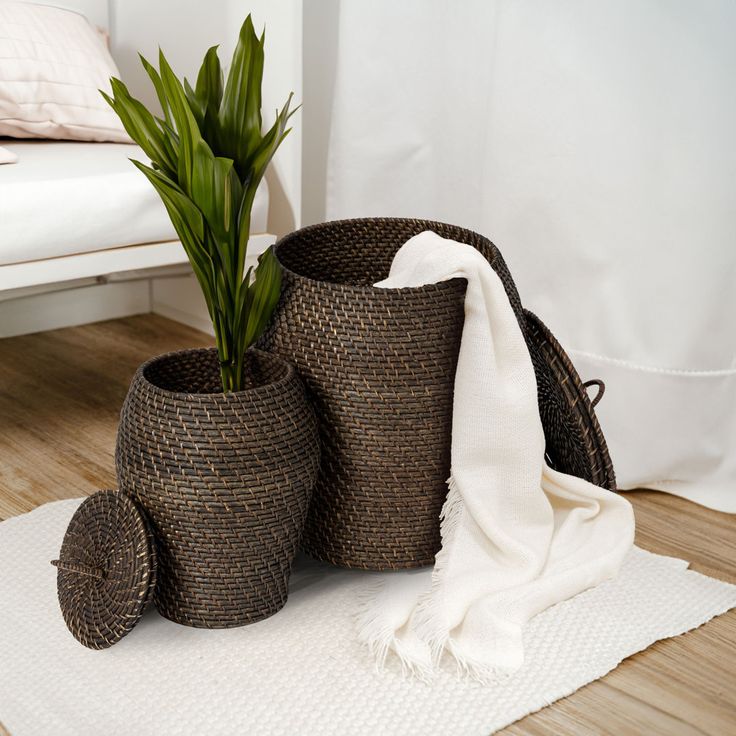 three woven baskets with plants in them sitting on a wooden floor next to a white bed