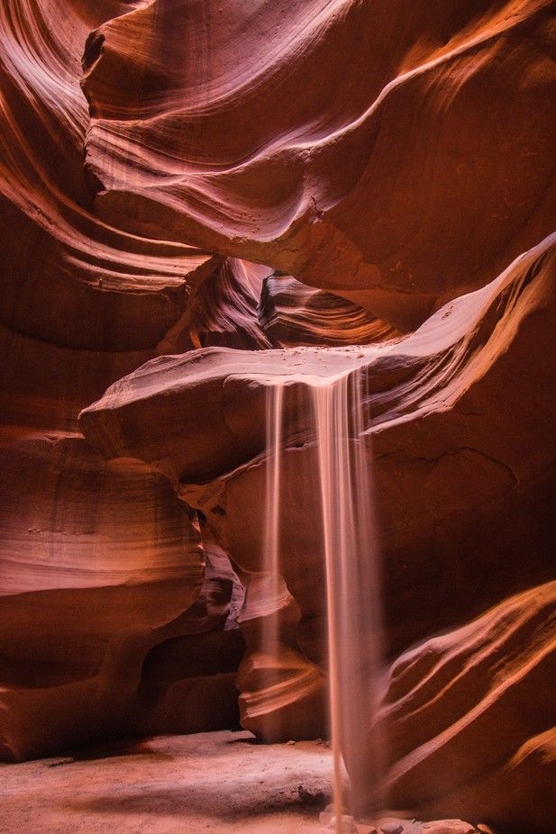 a small waterfall cascading down the side of a large rock formation in a canyon