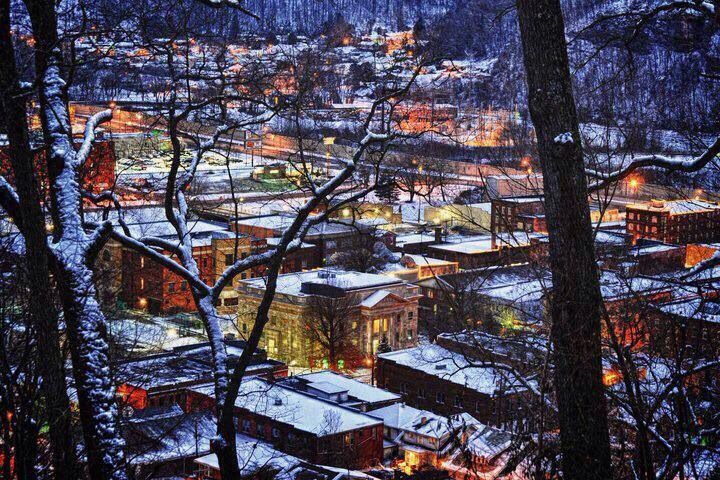 the city is lit up at night in the winter time with snow on the ground