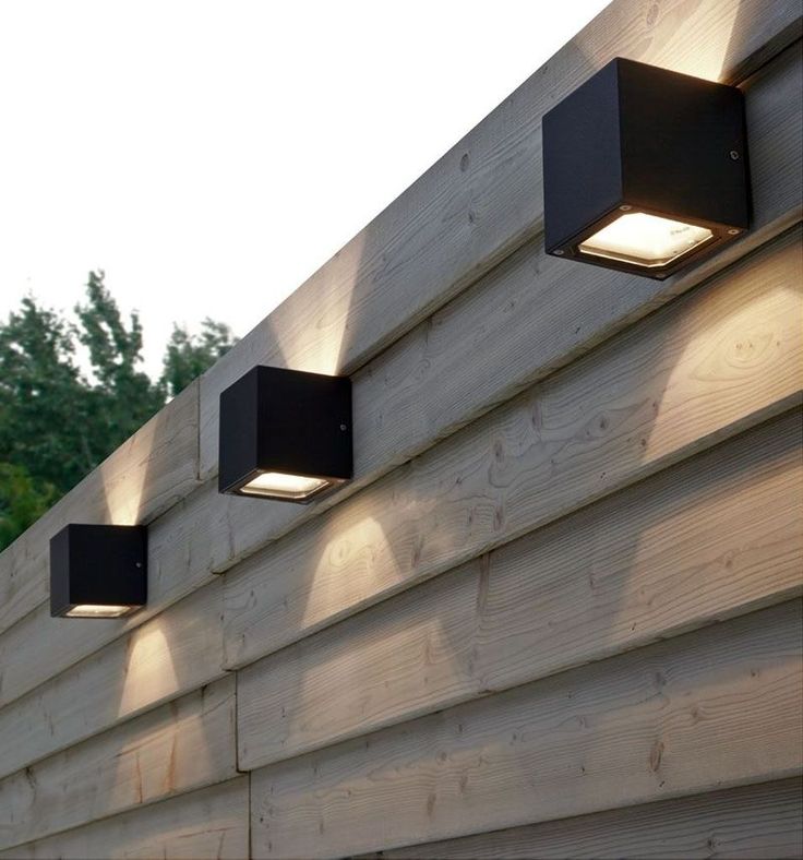 three lights are on the side of a wooden wall