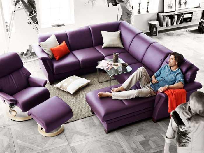 a man sitting on top of a purple couch in a living room next to a woman