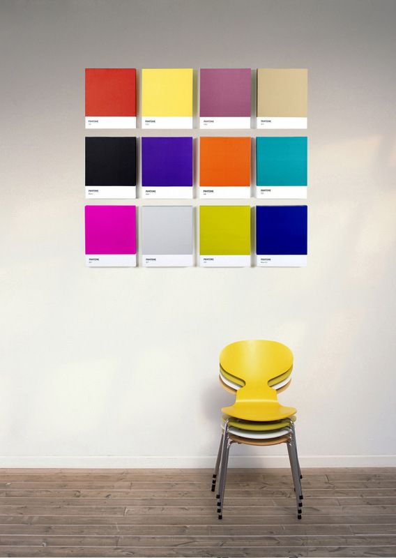 a yellow chair sitting in front of a white wall with color swatches on it