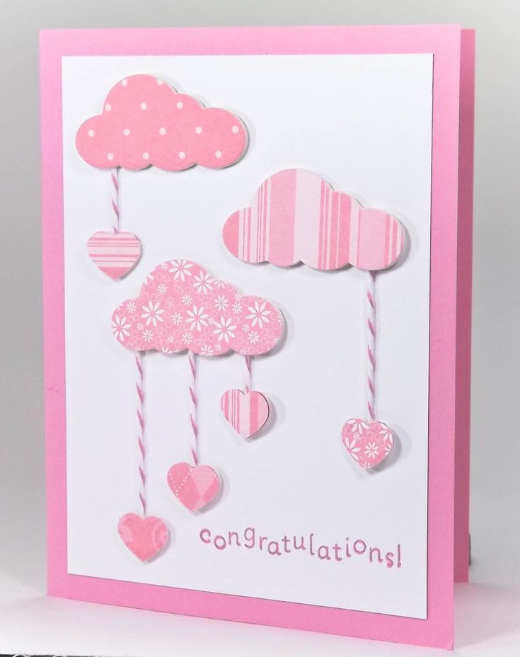 a pink and white card with hearts hanging from it's sides, on top of a