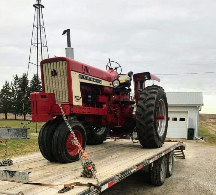 a red tractor is on the back of a flatbed trailer