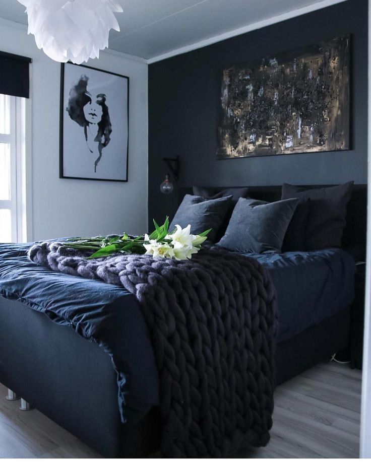 a bed with blue sheets and pillows in a bedroom next to a painting on the wall