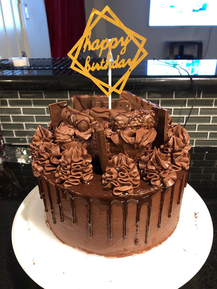 a birthday cake with chocolate frosting and flowers on top is sitting on a plate