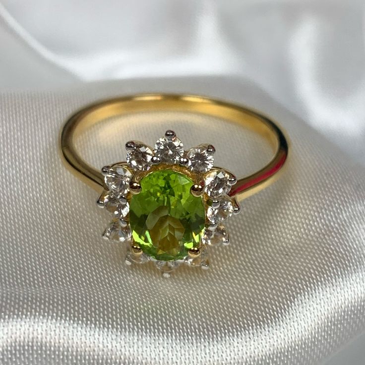 a yellow gold ring with an oval cut peridolite surrounded by small white diamonds