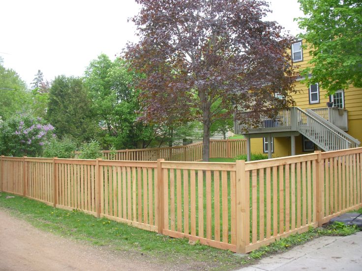 a wooden fence in front of a yellow house