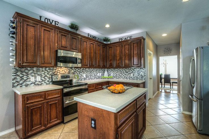 a large kitchen with wooden cabinets and stainless steel appliances, along with tile flooring