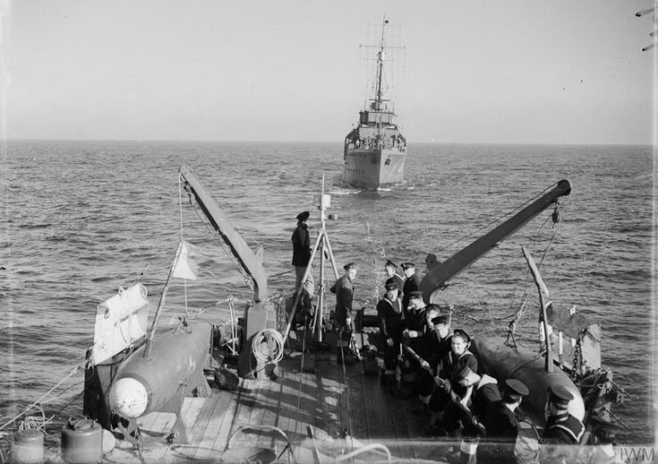 an old black and white photo of people on the deck of a boat with a ship in the background