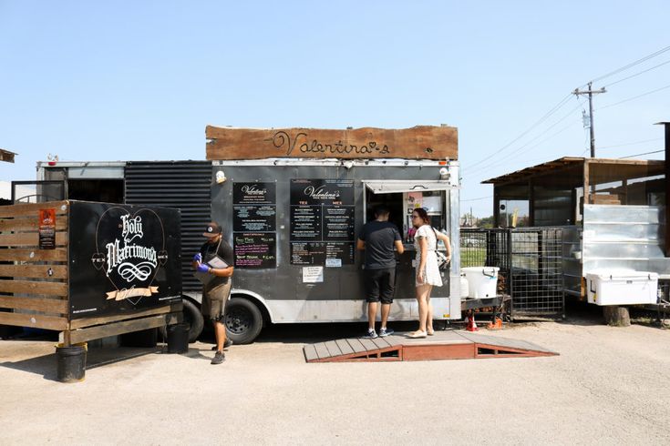 three people standing in front of a food truck