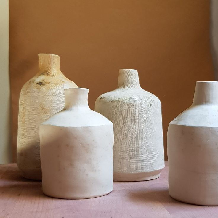 three white vases sitting on top of a wooden table