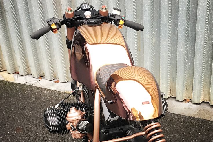 a motorcycle parked in front of a metal wall with a fan on it's back end