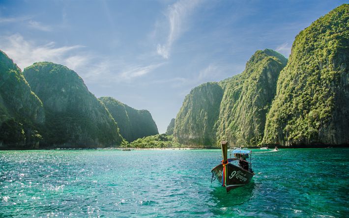 a boat floating on top of a large body of water next to green mountain covered hills