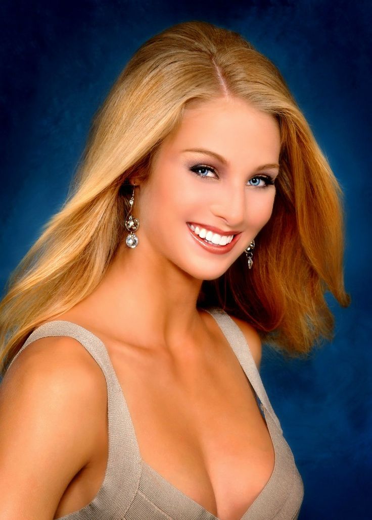 a beautiful blonde woman in a gray dress posing for a photo with her hair blowing back