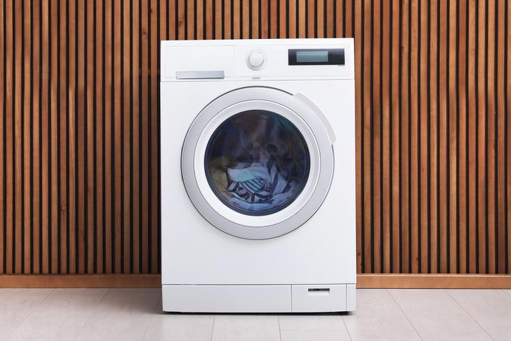 a white washing machine sitting in front of a wooden wall with a dog inside it