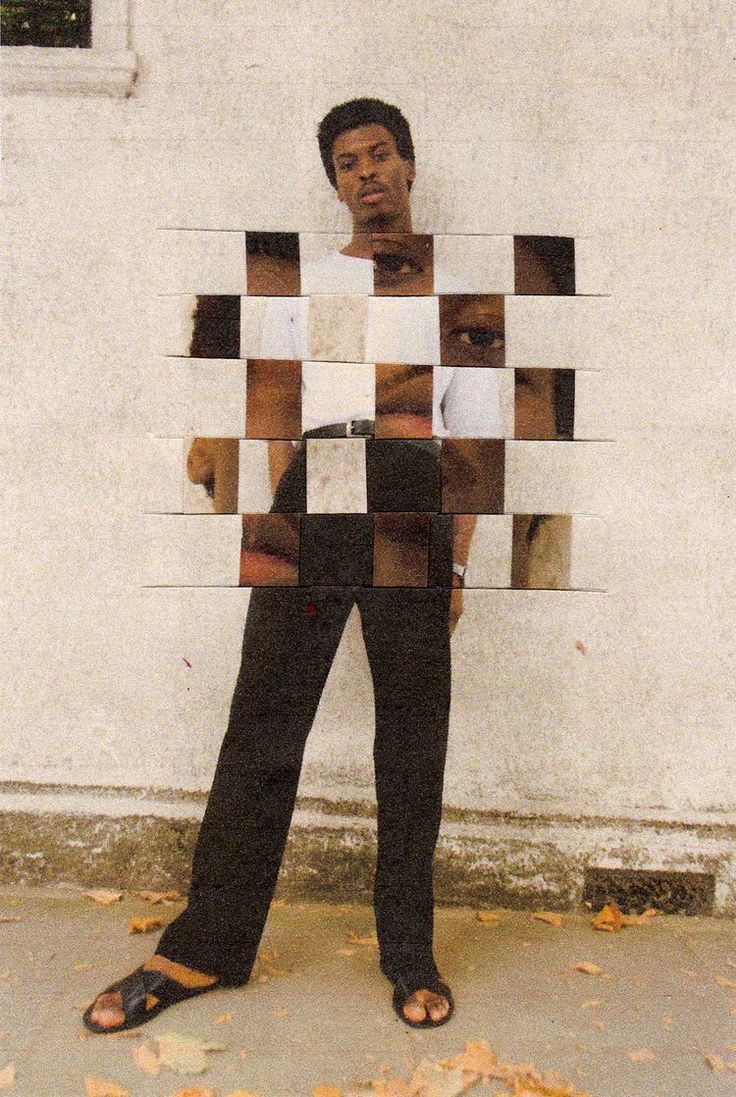 a man standing in front of a white wall holding a piece of paper with squares on it