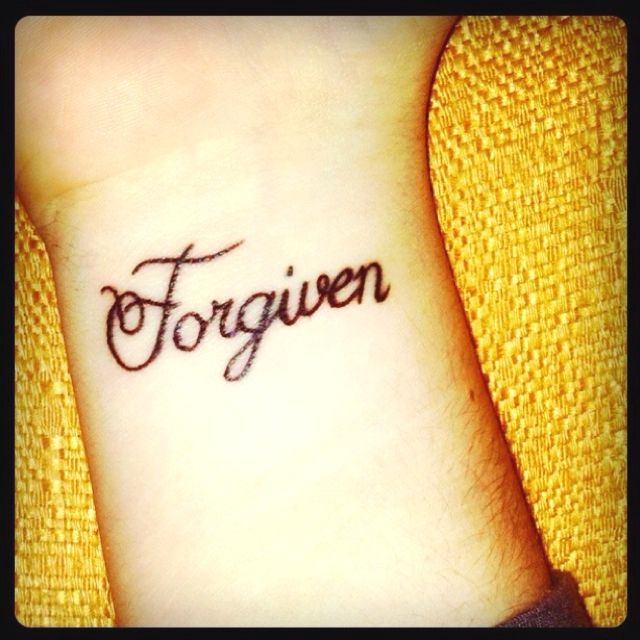 a woman's wrist tattoo with the word forgotten written in cursive font