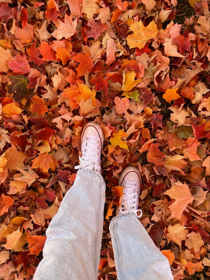 a person standing in front of a pile of leaves with their feet on the ground