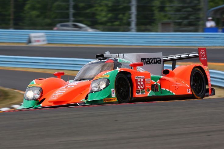 an orange and green race car driving on a track