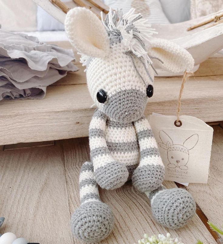 a crocheted stuffed animal sitting on top of a wooden table next to eggs