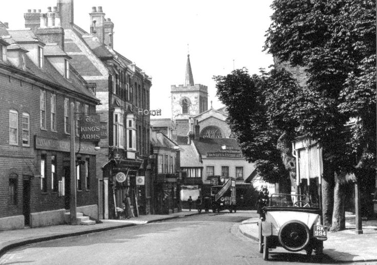 an old car is parked on the side of the road in front of some buildings