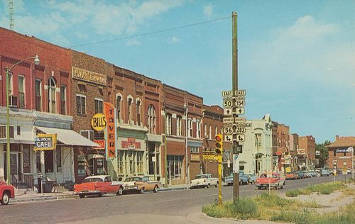 an old photo of a city street with cars parked on the side of the road