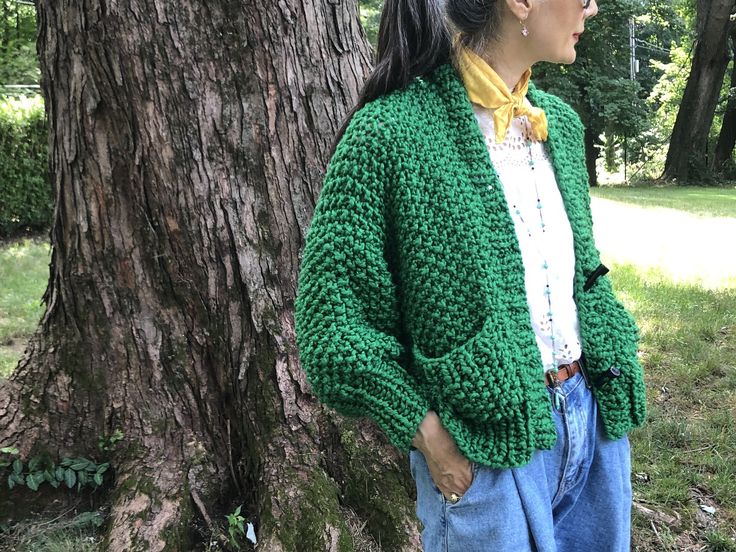 a woman standing next to a tree wearing a green cardigan