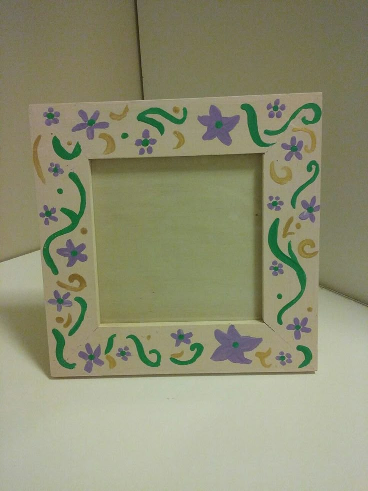 a small wooden frame with flowers and vines painted on the outside, sitting on a table