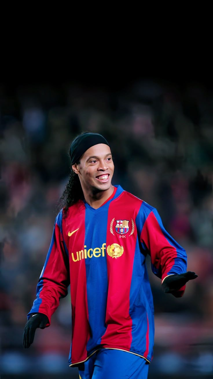 a man in a red and blue soccer uniform smiles at the camera while holding his hands out