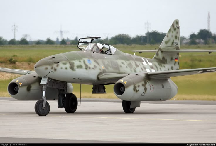 a fighter jet sitting on top of an airport tarmac with grass in the background