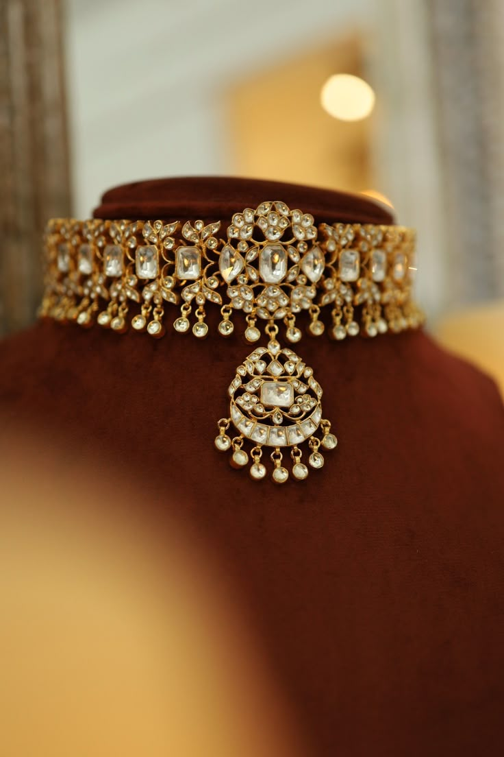 a gold necklace on display in a jewelry store, with other items around the neck