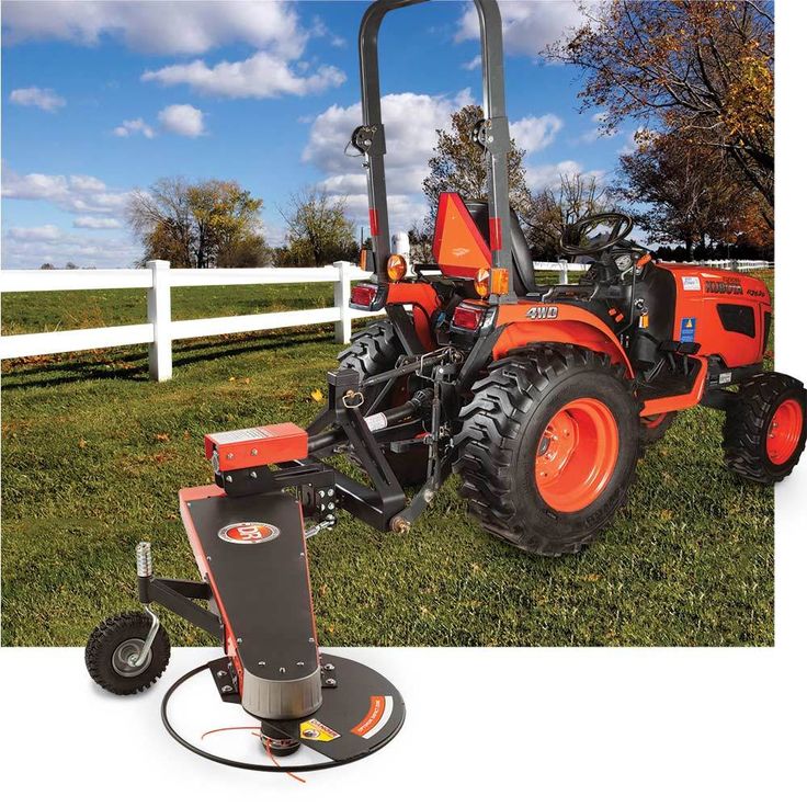 an orange tractor parked in the grass next to a white fence